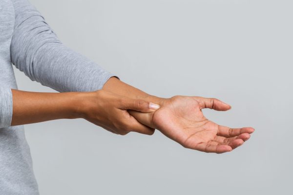 Close up of black woman holding her wrist, having pain from using computer. Office syndrome, joint pain by occupational disease.